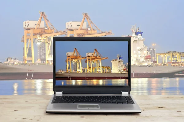 Laptop op houten tafel met poort magazijn en lading schip backgr — Stockfoto