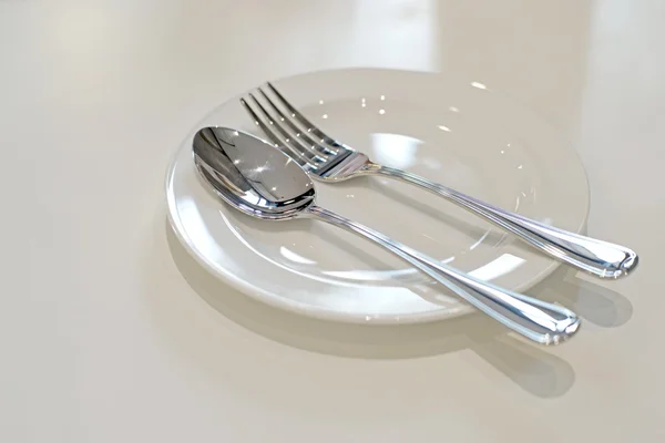 Spoon and fork on white plate — Stock Photo, Image