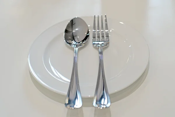 Ложка и вилка на белой тарелке — стоковое фото