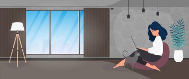 Kız bir sedirin üzerinde oturuyor ve dizüstü bilgisayarda çalışıyor. Dizüstü bilgisayarı olan bir kadın büyük bir puf üzerinde oturur..