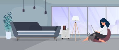 Kız bir sedirin üzerinde oturuyor ve dizüstü bilgisayarda çalışıyor. Dizüstü bilgisayarı olan bir kadın büyük bir puf üzerinde oturur..