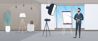 Takım elbiseli, kravatlı bir adam kameraya sunum yapıyor. Öğretmen bir ders yazıyor. Blog yazma, çevrimiçi eğitim ve konferans kavramı. Bir tripoda kamera, yumuşak kutu.