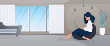 Kız bir sedirin üzerinde oturuyor ve dizüstü bilgisayarda çalışıyor. Dizüstü bilgisayarı olan bir kadın büyük bir puf üzerinde oturur..