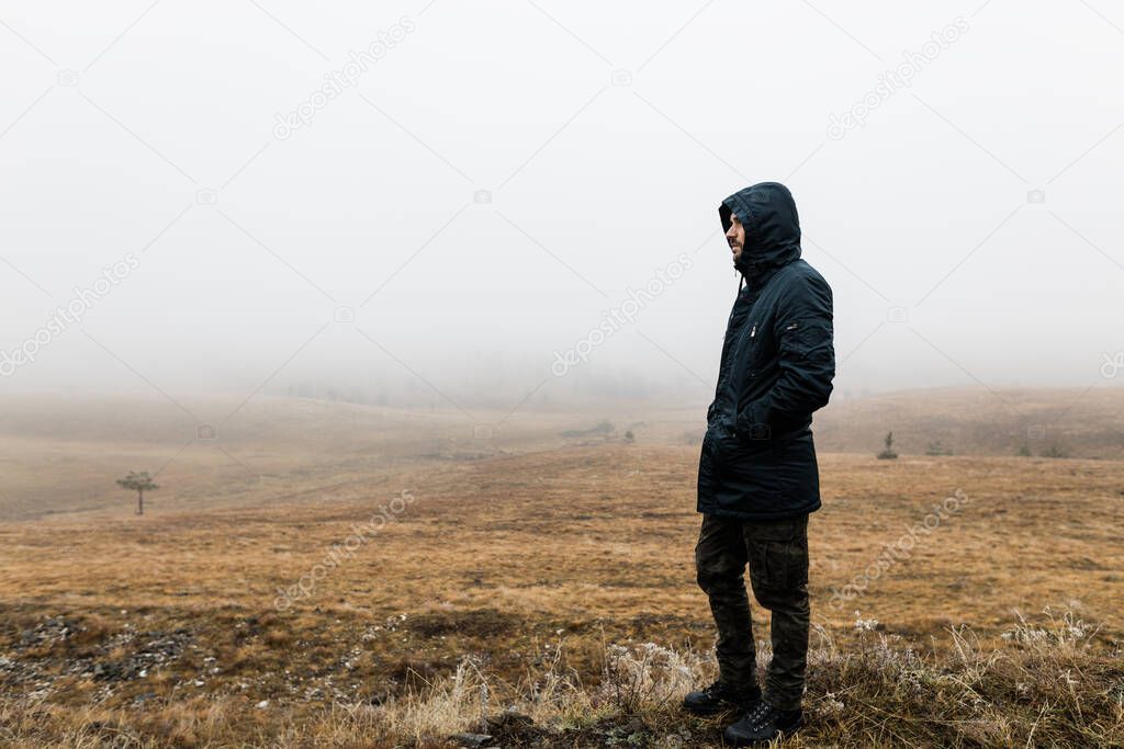 Young man exploring nature on a wet winter morning in the mountains