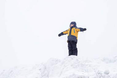 Sarı ceketli küçük bir çocuk kışın elleri havada bir dağın tepesinde durur. Zirvelerin fatihi. Çocuk bir kuş gibi uçtuğunu hayal ediyor.