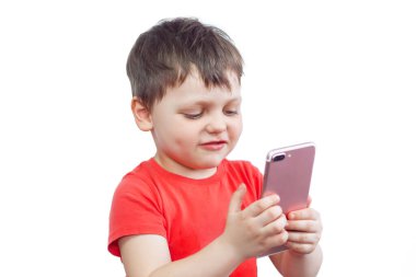 Çocuk telefonu anlamaya çalışmaktadır. Kırmızı tişörtlü küçük bir çocuk telefonunda uygulama kullanıyor.