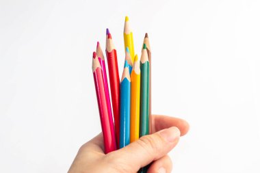 Beyaz arka planda izole edilmiş bir kadının elindeki renkli kalemler.