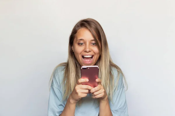 Молода Кавказька Збуджена Вражена Захоплена Блондинка Посміхається Тримаючи Мобільний Телефон — стокове фото