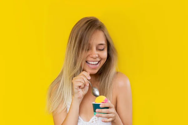 윗면에 금발의 여성이 웃으며 노란색 배경에 고립된 콘에서 아이스크림 셔벗을 — 스톡 사진