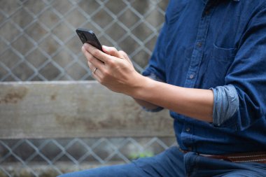 Akıllı telefon kullanan bir adama yakın plan, açık havada, gündüz vakti.