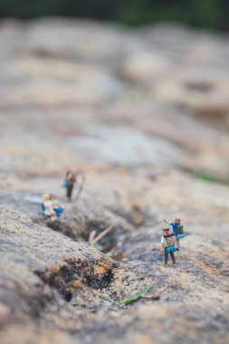Minyatür yürüyüşçü figürünün eğlenceli konsepti kayalarda, açık havada, gündüz vakti