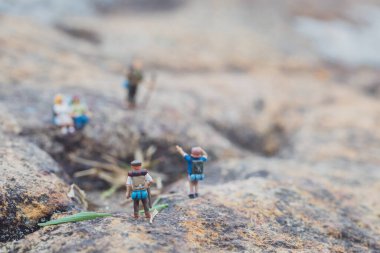 Minyatür yürüyüşçü figürünün eğlenceli konsepti kayalarda, açık havada, gündüz vakti