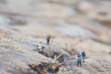 Minyatür yürüyüşçü figürünün eğlenceli konsepti kayalarda, açık havada, gündüz vakti