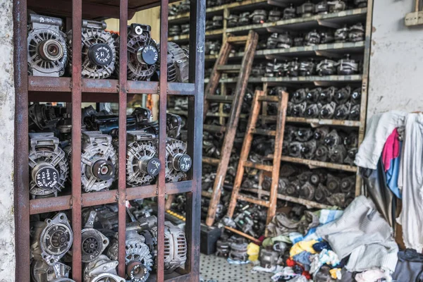 Otomobil tamirhanesinde yedek dişli ve motor parçaları, karanlık ve kirli.