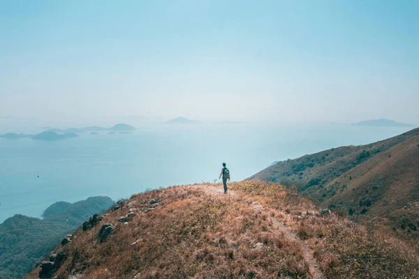 背包客徒步旅行者在海边的山上行走 户外白天 — 图库照片