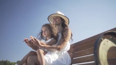 Annesiyle küçük güzel bir kız bankta oturur ve parkta yürür.