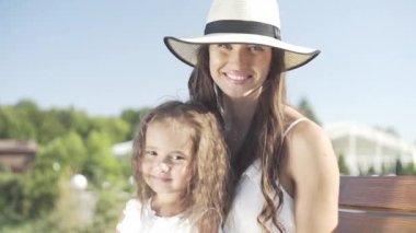 Annesiyle küçük güzel bir kız bankta oturur ve parkta yürür.