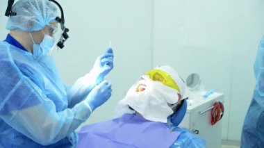 Diş hekimi asistanı diş fırçasıyla dişlerini fırçalayan bir diş hekimi.