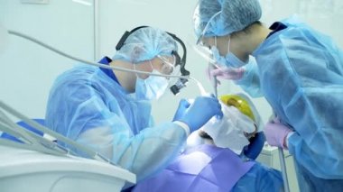 Diş hekimi asistanı diş fırçasıyla dişlerini fırçalayan bir diş hekimi.