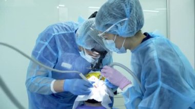 Diş hekimi asistanı diş fırçasıyla dişlerini fırçalayan bir diş hekimi.