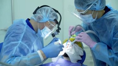 Diş hekimi asistanı diş fırçasıyla dişlerini fırçalayan bir diş hekimi.