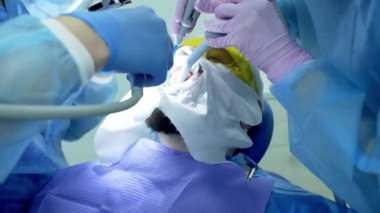 Diş hekimi asistanı diş fırçasıyla dişlerini fırçalayan bir diş hekimi.