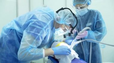 Diş hekimi asistanı diş fırçasıyla dişlerini fırçalayan bir diş hekimi.