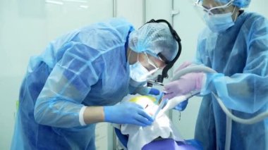 Diş hekimi asistanı diş fırçasıyla dişlerini fırçalayan bir diş hekimi.