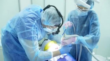 Diş hekimi asistanı diş fırçasıyla dişlerini fırçalayan bir diş hekimi.