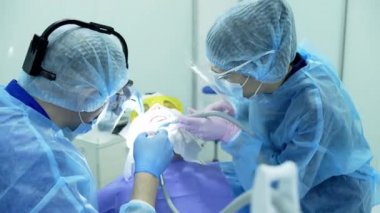 Diş hekimi asistanı diş fırçasıyla dişlerini fırçalayan bir diş hekimi.