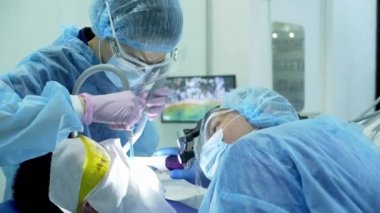 Diş hekimi asistanı diş fırçasıyla dişlerini fırçalayan bir diş hekimi.