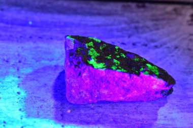 Mineral flouresciing green and pink under a UV light. clipart