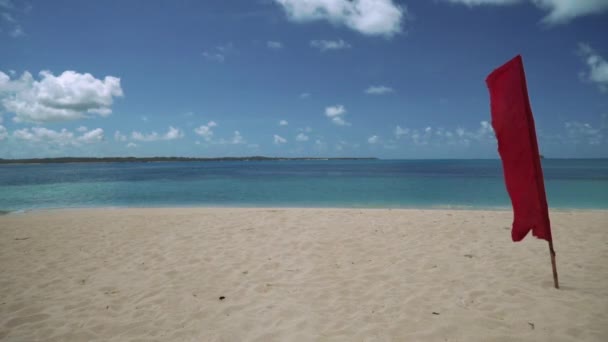 Drapeau rouge sur une plage de sable blanc sur une île tropicale — Video