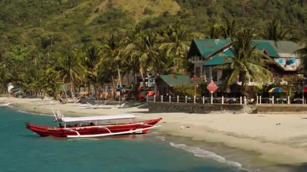 Rotes Auslegerboot am sauberen weißen Sandstrand mit schönem Haus, Philippinen — Stockvideo