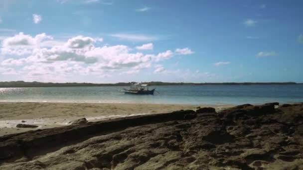 Βάρκα Outrigger κοντά στην παραλία με λευκή άμμο και μερικά βράχια — Αρχείο Βίντεο