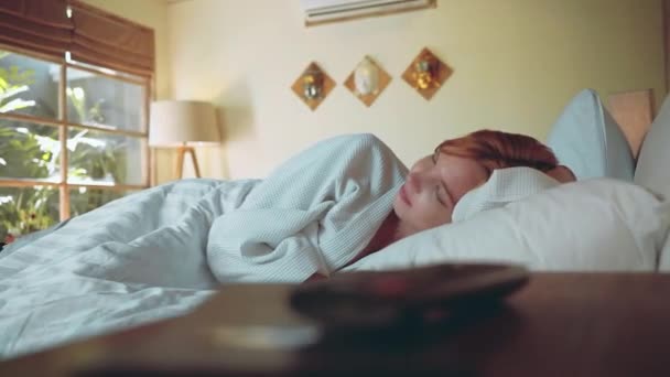 Девушка спит в постели в светлой комнате — стоковое видео