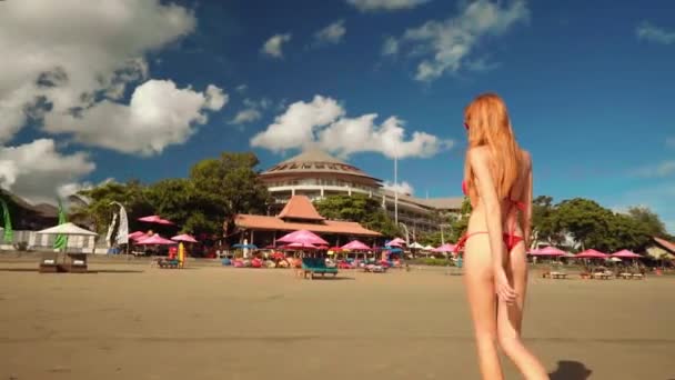 Young slim woman in red bikini walking on beach, Bali — Stock Video