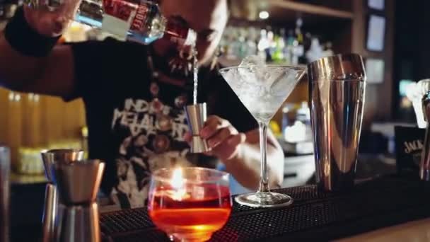 Barman com piercings e dreadlocks fazendo coquetel, derramando vodka — Vídeo de Stock