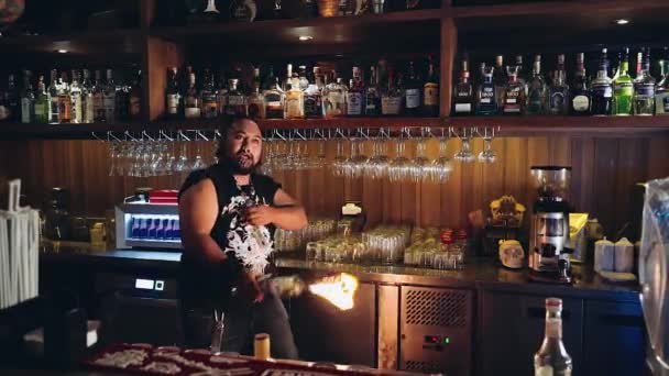 Artistic bartender with piercings, dreadlocks juggling bottle torch and shaker — Stock Video