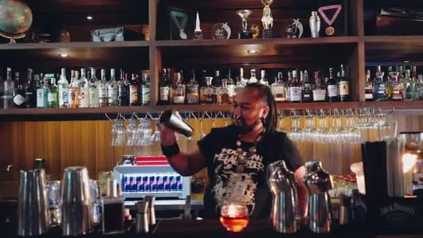 Barman z piercing i dredy zaczyna żonglerka butelka palnika i shaker — Wideo stockowe