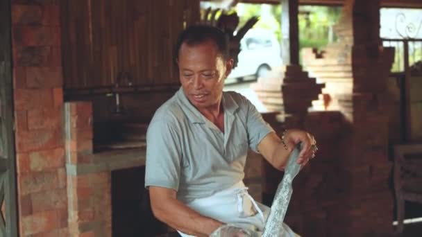 Balinese cook grating coconut into big clay bowl — Stock Video