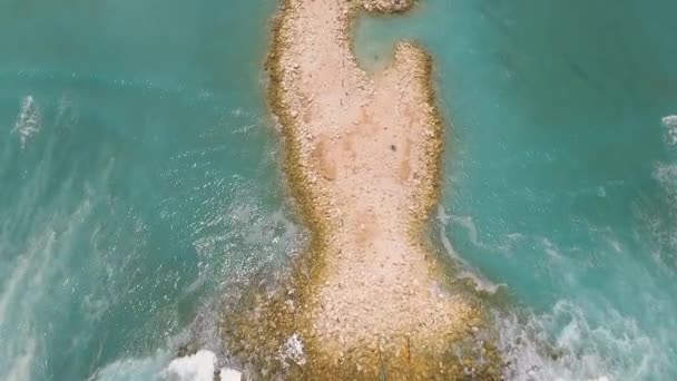 Luftaufnahme eines künstlichen Hügels im Meer und einer Serpentinenstraße dahinter — Stockvideo