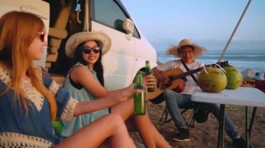 Camper van yakınındaki plaj piknik üzerinde üç arkadaş