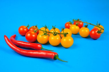 Mavi arka planda sarı ve kırmızı kiraz domatesleri ve kırmızı biberler..