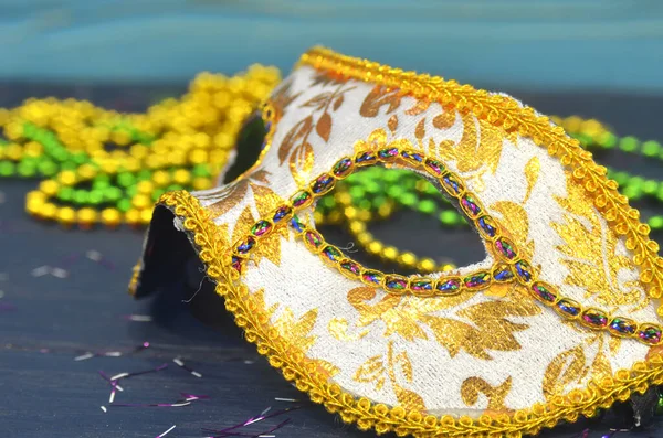 Máscara de Mardi gras y cuentas sobre un fondo de madera. Accesorios de carnaval Madi Gras, confeti, mascarilla festiva, veneciana o de carnaval. Mascarada concepto de celebración — Foto de Stock