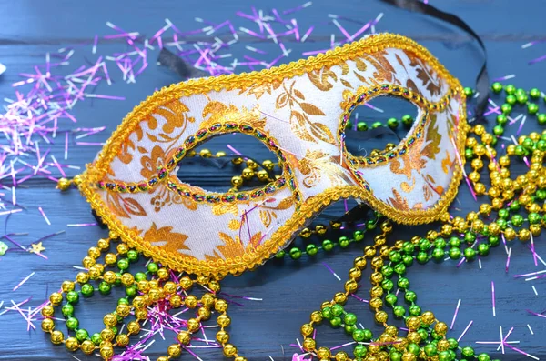 Mardi gras mask and beads on a wooden background. Madi Gras carnival accessories, confetti, Festive, venetian or carnivale mask. Masquerade celebration concept