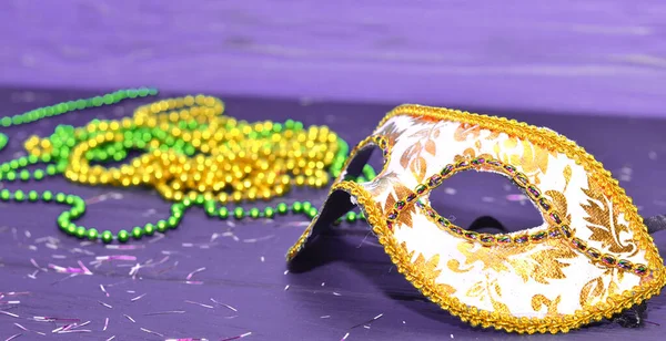 Máscara de Mardi gras y cuentas sobre un fondo de madera. Accesorios de carnaval Madi Gras, confeti, mascarilla festiva, veneciana o de carnaval. Mascarada concepto de celebración — Foto de Stock