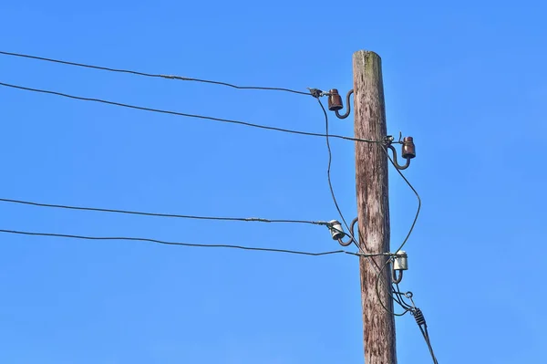 An old wooden pole of an overhead power line in the countryside.