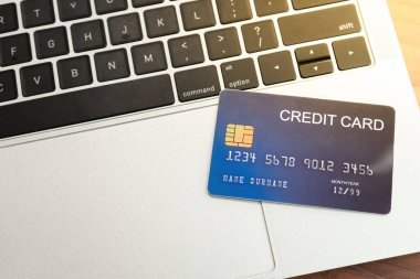 Laptop klavyesindeki mavi kredi kartının yakın çekimi. İnternet satın alma kavramı