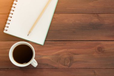 Kahve fincanda servis edilir, bir kalem ve defterin yanına konur.